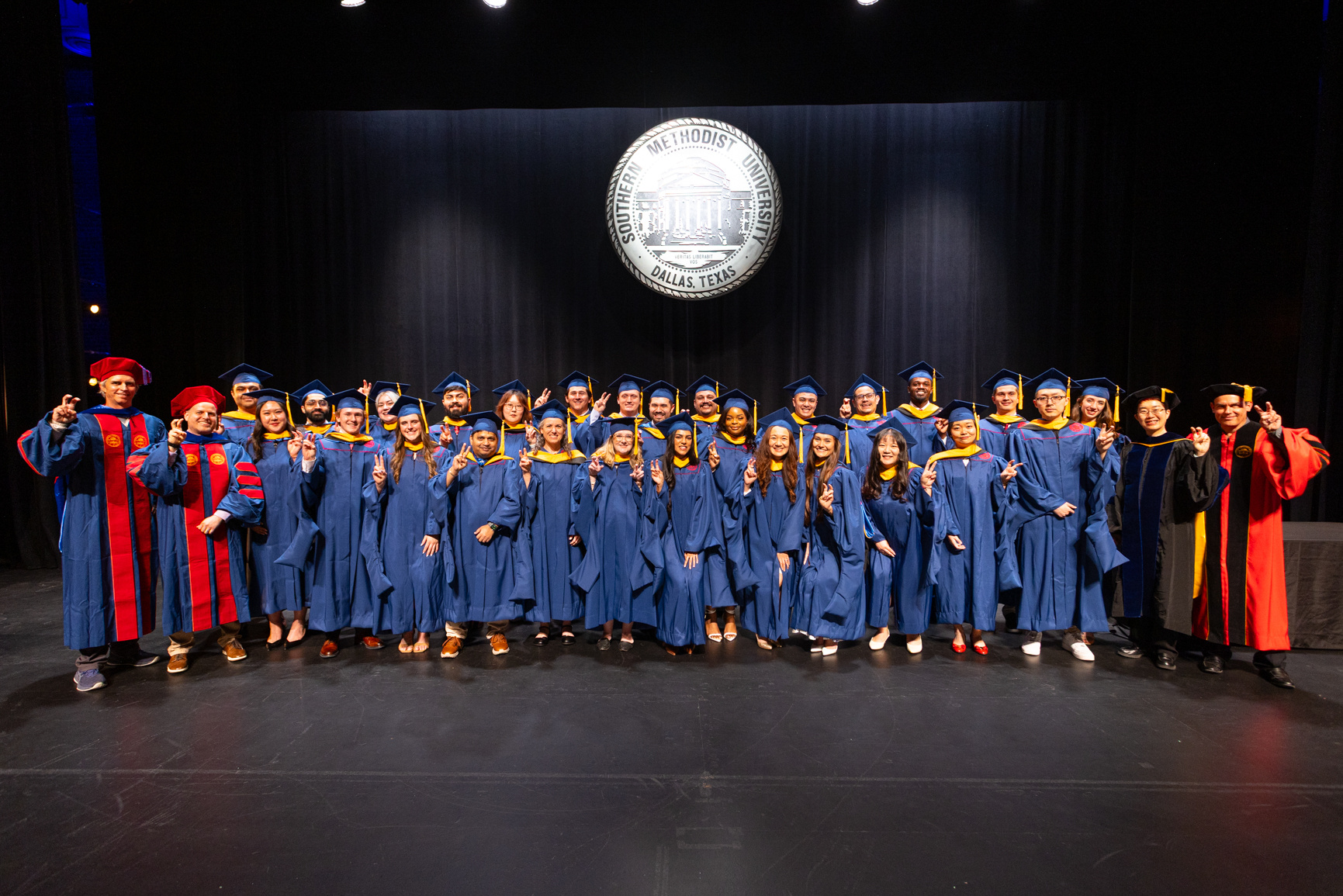 Recent graduates of the Master of Science in Data Science program pose for a group picture with faculty shortly after their diploma ceremony inside McFarlin Auditorium. Series produced for Southern Methodist University marketing material, 2026.