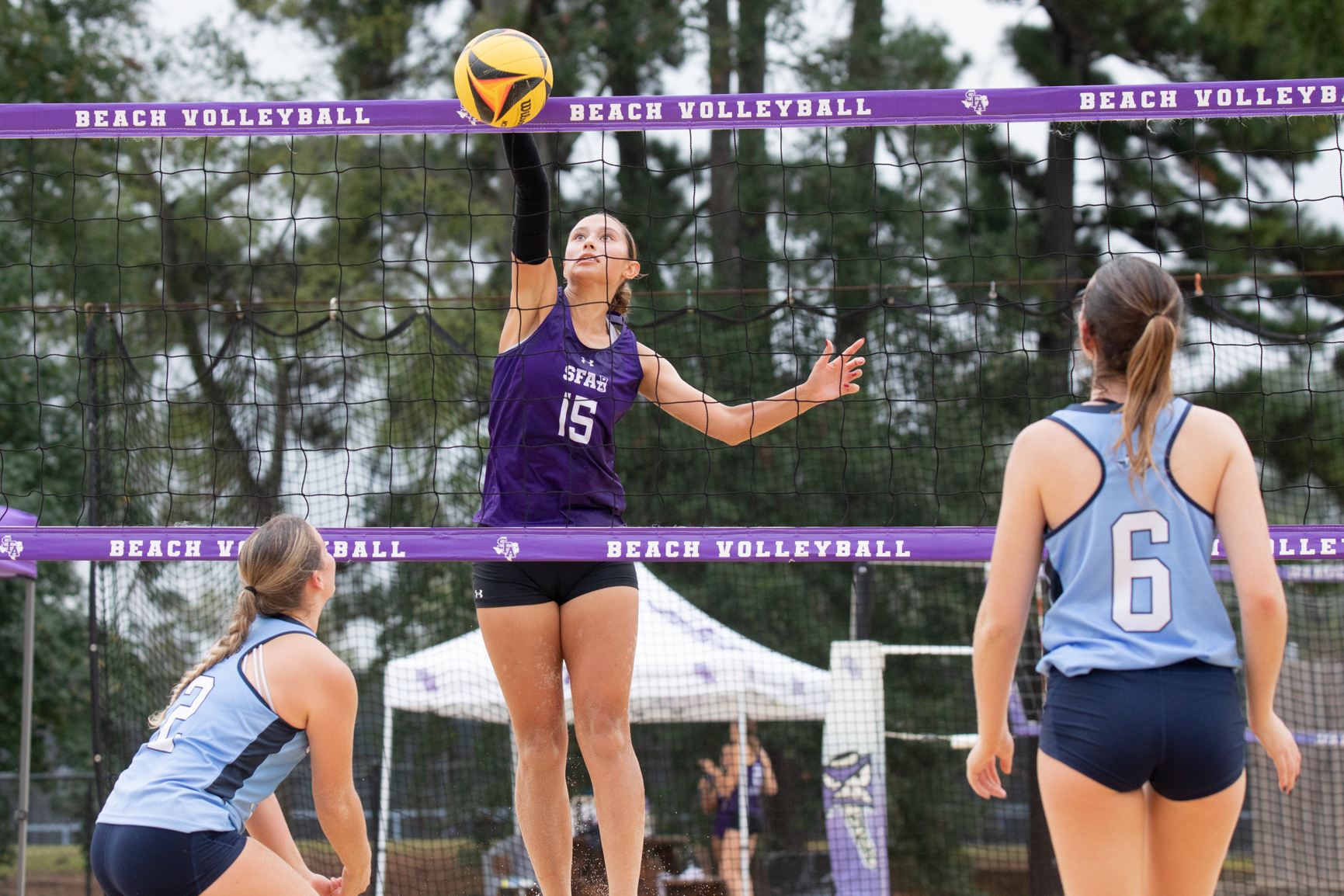 SFA’s sophomore Victoria Simmang spikes the ball as ETBU junior Bailee Kitchen (left) and ETBU freshman Camille Freeman miss the block.
